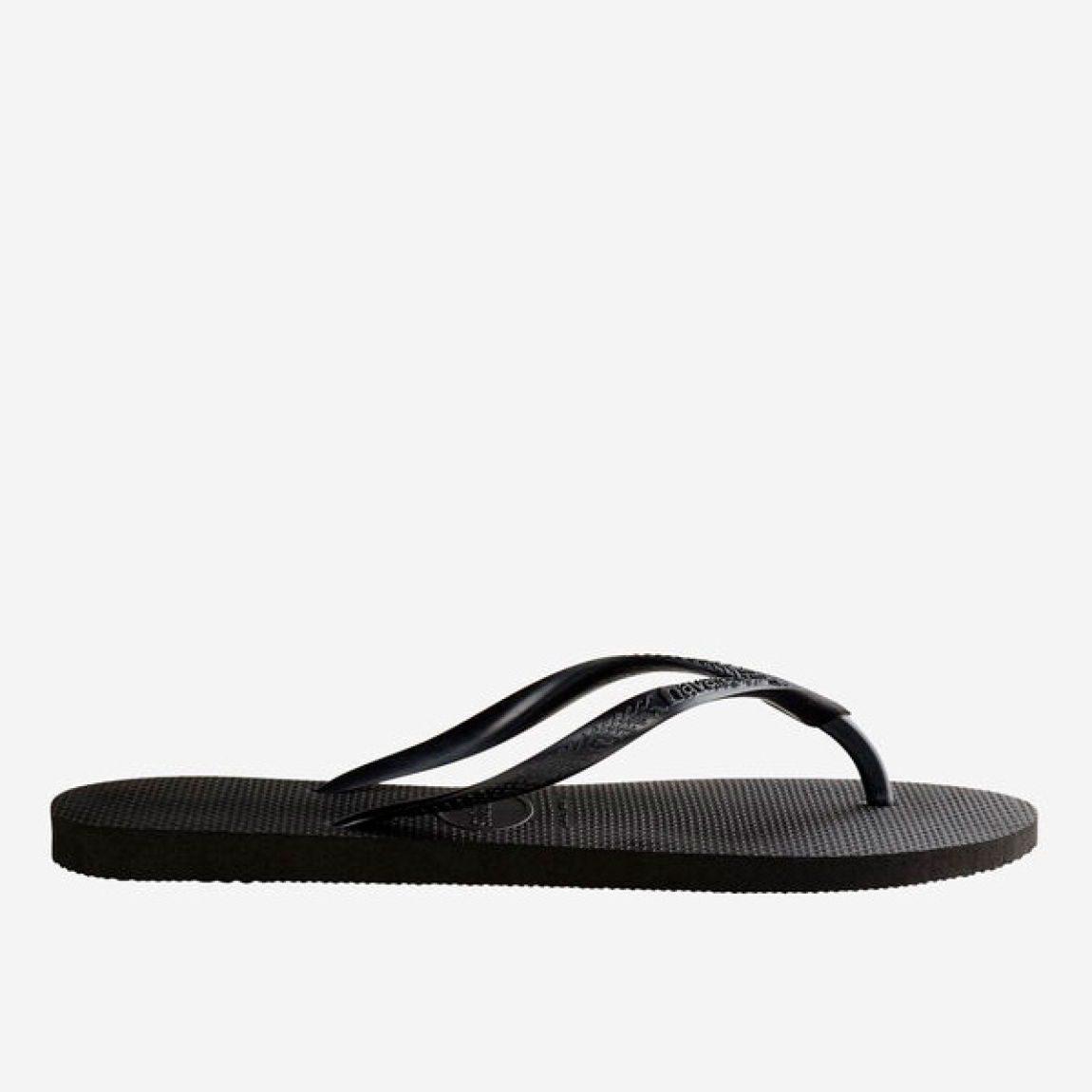 Chanclas de la marca Havaianas, modelo SLIM FC. Chancas elaboradas en plástico color negro. Chanchas con ligereza, la suela de foma suave acompaña el pie sin pesar y el acabado antideslizante te da seguridad tanto en la arena como en el paseo de la tarde. El diseño se centra en estilizar el pie con unas tiras finas que aportan un brillo discreto y muy favorecedor. Cada detalle está pensado para que las chanclas Havaianas SLIM funcionen como una extensión natural de tu estilo: limpias, depuradas y con ese punto elegante que diferencia unas chanclas premium de unas básicas.