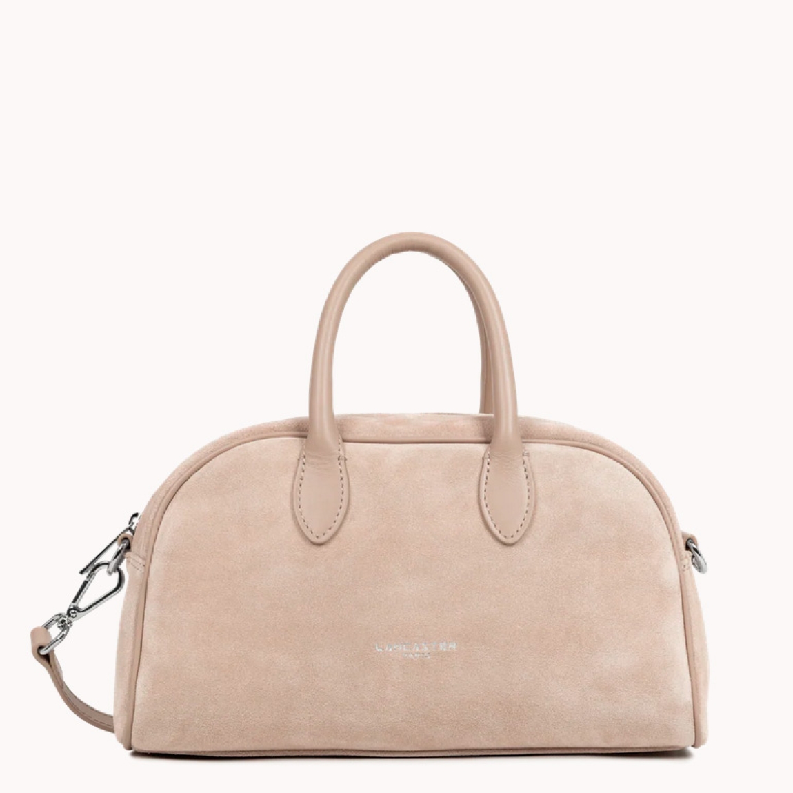 Bolso de la marca Lancaster, modelo BOWLING. Elaborado en ante color beig. Cierre con cremallera dos asas fijas. Además, de asas extraíbles para llevarlo cruzado. Cuenta con un bolsillo interior simple y un bolsillo interior con cremallera. Bolso Lancaster BOWLING perfecto para llevarlo a todos lado. Medidas: alto 18cm y ancho 29cm.