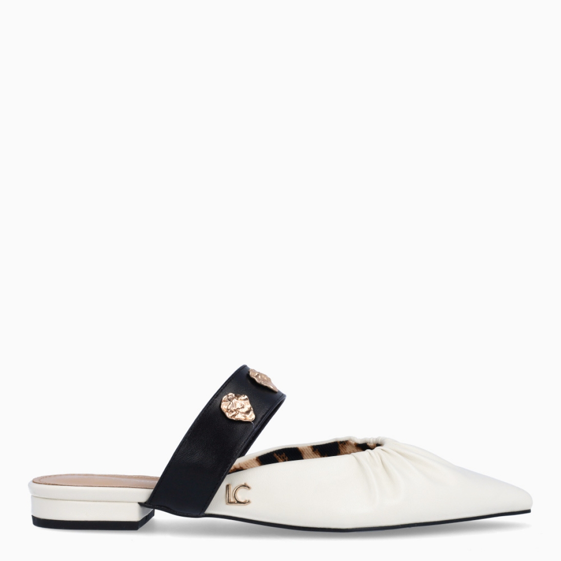 Salones destalonados de la marca Lola Casademunt, modelo ELOISE. Elaborado en piel color blanco con efecto corrugado, punta de lápiz y detalle de tira negra con adornos dorados en pala. Salones planos para máxima comodidad. Salones Lola Casademunt ELOISE, ideal para combinar con atuendos casuales o de oficina.