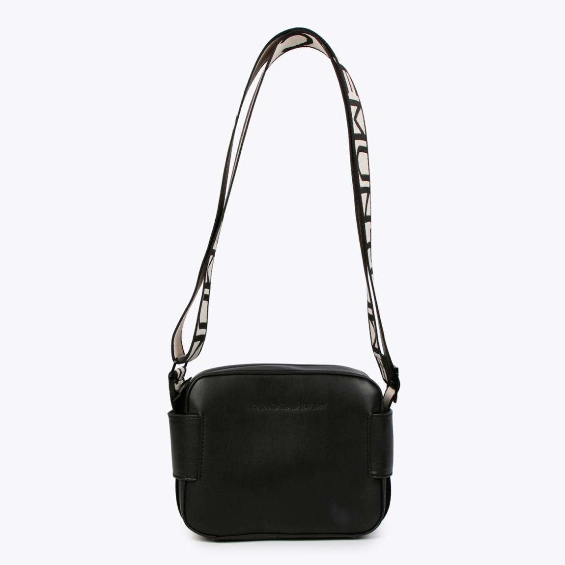 Bolso de la marca Lola Casademunt, modelo NOA. Bolso bandolera elaborado en piel color negro con logo de la marca en la parte frontal. Cuenta con compartimento interior amplio y un bolsillo interior. Cierre con cremallera y asa extraíble con estampado de la marca en negro y blanco. Medidas del bolso: alto 14cm y ancho 18cm. Este bolso Lola Casademunt NOA es un clásico, con un estilo versátil y atemporal. Perfecto para combinarlo con todos tus looks!