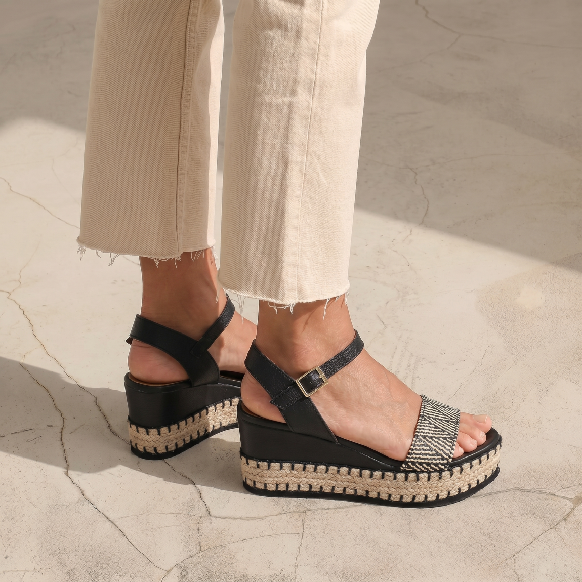 Sandalias de la marca Itse, modelo FLORA. Exterior de las sandalias en rafia color negro y blanco. Interior de las sandalias en piel color negro. Cierre de las sandalias Itse con hebilla en tobillo y cuña de 8cm de altura. Estas sandalias Itse FLORA son el complemento ideal para crear diferentes looks esta temporada, y sobre todo, gozar de una comodidad espectacular en tu día a día.
