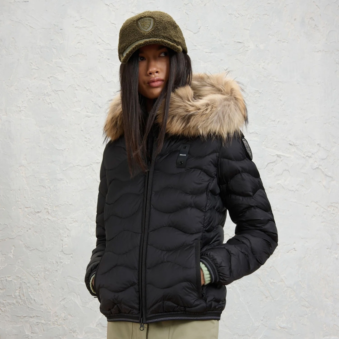 Chaqueta plumífera de la marca Blauer, modelo ALDIE. Chaqueta acolchada con ondas horizontales, embellecido con un borde de capucha en piel auténtica extraíble. Esta prenda icónica de Blauer ofrece un relleno natural (90/10 gr.175) cálido y no voluminoso. Realizado en nylon brillante color negro con forro en contraste, presenta un elegante parche con purpurina. Chaqueta Blauer ALDIE, ideal para los días fríos de esta temporada!