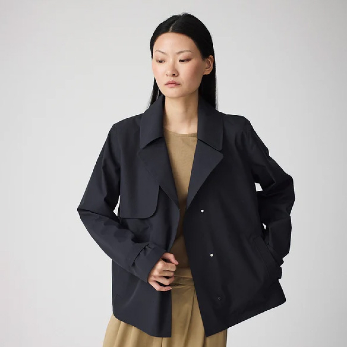 Chaqueta corta impermeable de la marca Tanta, modelo NIWL. Chaqueta sin costuras Niwl está confeccionado en tejido de sarga de poliéster color azul marino. Es 100% impermeable y cuenta con todas las costuras selladas para una protección superior. Los detalles de la prenda incluyen un canesú en la espalda y otro en el lado derecho de la parte delantera, botones a presión ocultos y una capucha desmontable con cordón ajustable. Diseñado con un corte impecable, esta chaqueta Tanta, modelo Niwl combina elegancia con una alta funcionalidad.