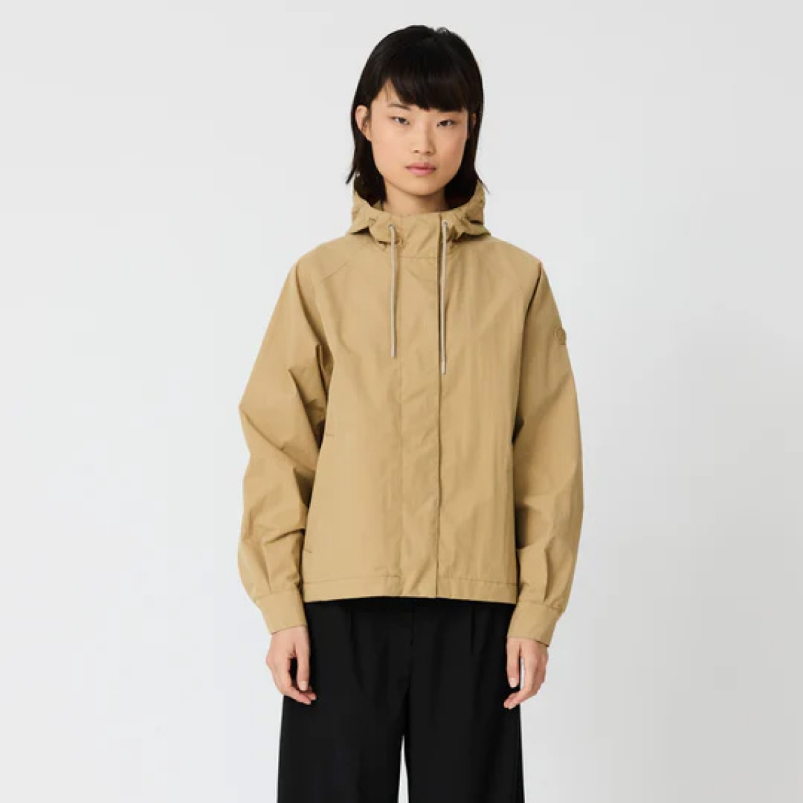 Chaqueta impermeable corta de la marca Tanta, modelo DHUDA. Chaqueta Tanta de corte holgado está confeccionada con un tejido de mezcla de algodón impermeable color camel. Este material atemporal es transpirable y resistente al viento. Los detalles de la prenda incluyen costuras selladas, mangas raglán, una cremallera de doble cursor y cierres a presión ocultos. Su elegante silueta en línea A de esta chaqueta Tanta DUDHA cuenta con aberturas laterales redondeadas para un look más femenino. Una prenda indispensable en tu armario esta temporada!