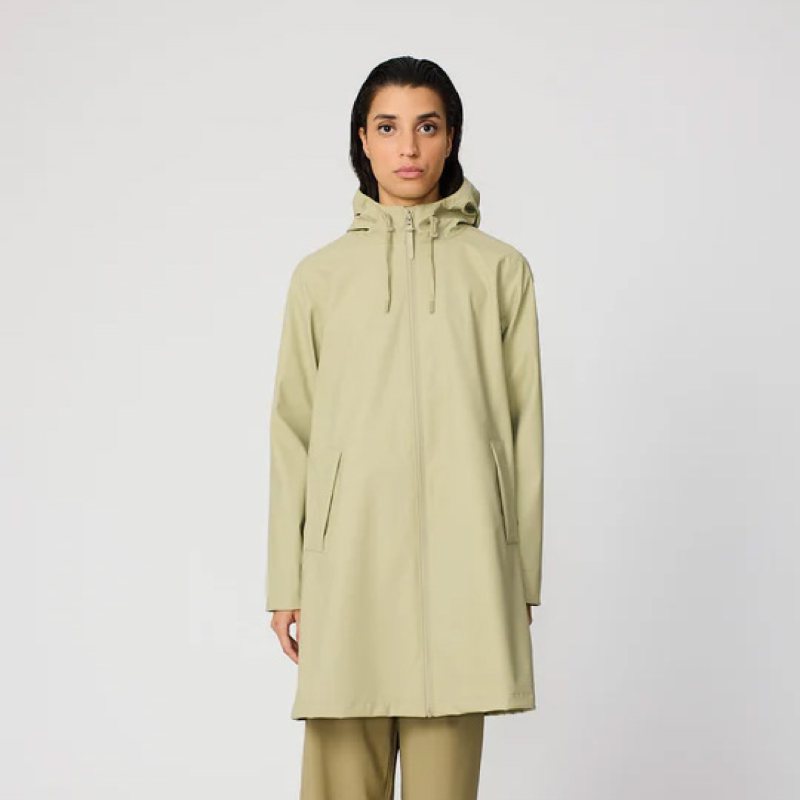 Chubasquero impermeable de mujer de la marca Tanta, modelo NUOVOLA. El impermeable Nuovola está confeccionado con nuestro icónico tejido de poliuretano color verde y cuenta con un pliegue en la espalda que aporta un volumen único en forma de A. Diseñado para el uso diario en temporadas de transición, El largo a mitad del muslo se complementa con una cremallera sellada en la parte delantera y con puños corta vientos en el interior de la manga para una protección adicional contra el clima más impredecible. Se ajusta a la talla real. Chaqueta larga lisa Tanta NUOVOLA ideal ara esta temporada!