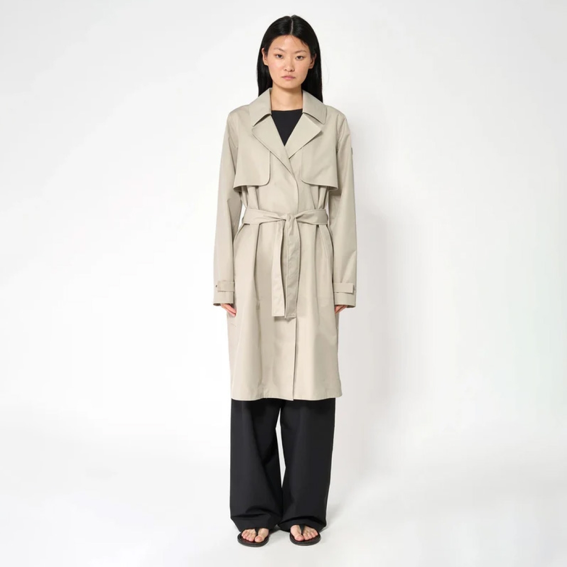 Chaqueta lisa larga de la marca Tanta, modelo TAGE. Chaqueta o gabarina impermeable sin costuras Tage está confeccionado en tejido de sarga de poliéster color beig. Es 100% impermeable y cuenta con todas las costuras selladas para una protección superior. Los detalles de la prenda incluyen dos canesús en la parte delantera y uno en la parte trasera, botones a presión ocultos, una cintura ajustable con cinturón y una capucha desmontable con cordón ajustable. Chaqueta Tanta dieñada con un corte impecable, el modelo Tage de Tanta combina elegancia con una alta funcionalidad.