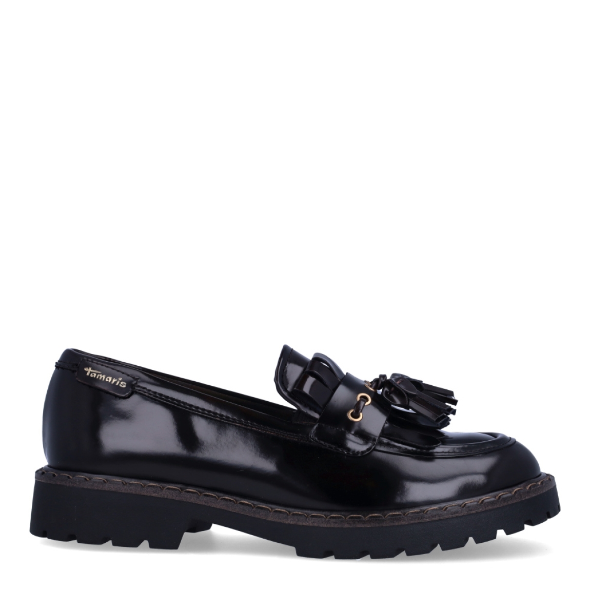 Zapatos estilo mocasín de la marca Tamaris, modelo CAMDEN. Confeccionados en piel de primera calidad con acabado acharolado marrón oscuro, destacan por su diseño clásico con detalle de flecos, borlas y herrajes dorados sobre el empeine. Su horma suave y flexible se adapta fácilmente a todo tipo de pie, ofreciendo un ajuste cómodo desde la primera puesta. Incorporan una plantilla acolchada de alto confort y una suela track de goma dentada con cerco pespunteado, perfecta para aislar del frío y asegurar un agarre impecable. Funcionan genial con calcetines a la vista y minifaldas de tablas, vestidos camiseros o tejanos anchos con jersey de punto grueso. ¡El calzado de tendencia clave para esta temporada!