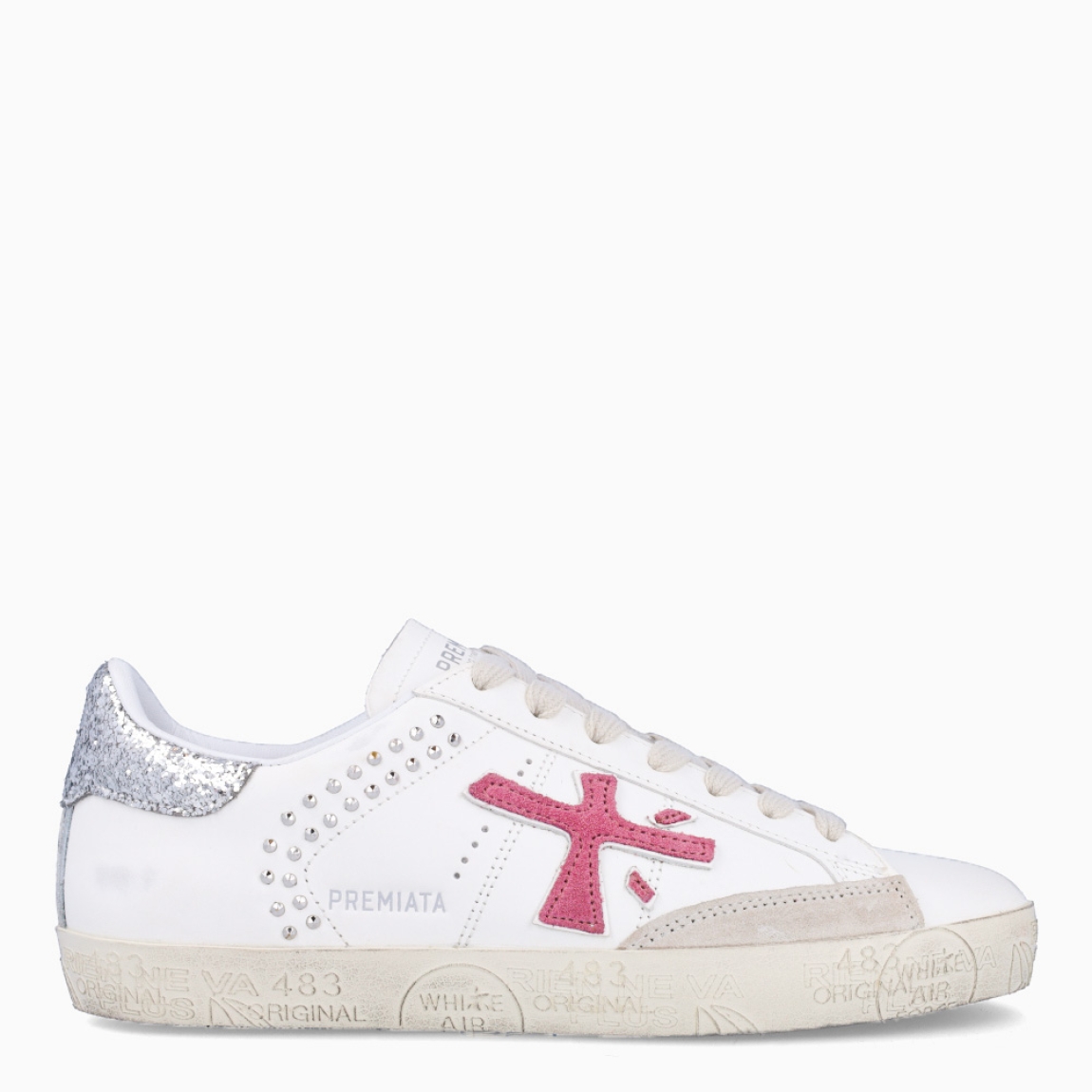Deportivas de la marca Premiata, modelo STEVEND. Exterior de las deportivas en piel color blanco con detalle en tachuelas y glitter plateado en el talón. Logo de color fucsia. Interior de las deportivas en piel color blanco. Cierre de las deportivas con cordones blancos. Deportivas Premiata Stevend tienen el diseño perfecto para temporada, no puede faltar este modelo clásico en tu armario!