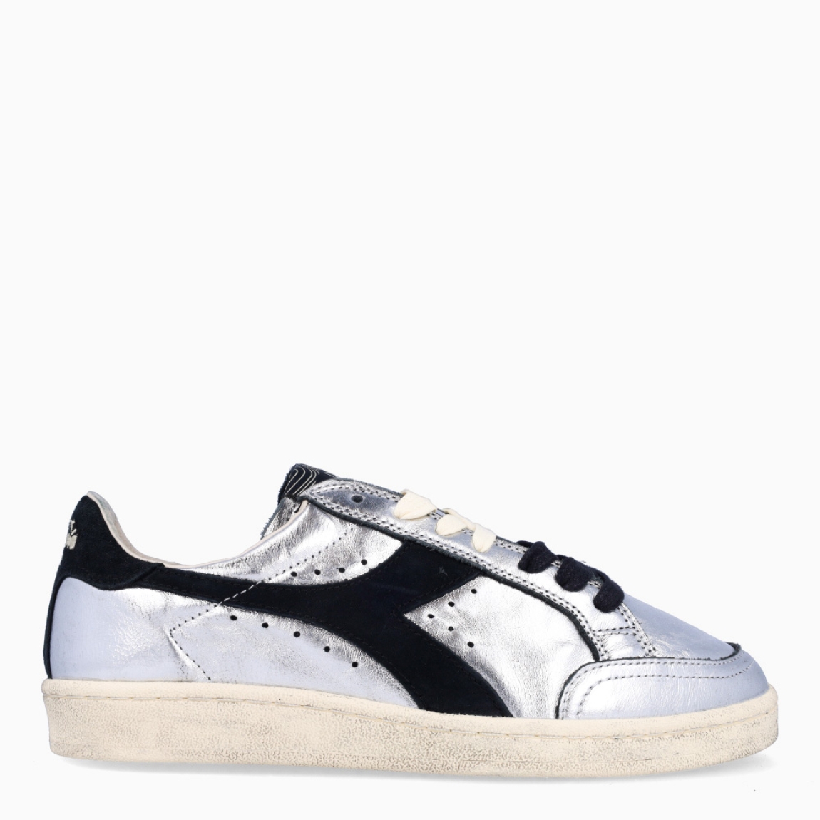 Deportivas de la marca Diadora, modelo ZULE. Exterior en piel color plata con efecto brillante y detalles en negro. Interior en textil color beig con plantilla acolchada y extraíble para máxima comodidad. Cierre con cordones de doble color: negro y beig. Suela de goma con cuña de 2cm de altura. Estas deportivas son unas clásicas ideales para llevar en tu día a día.