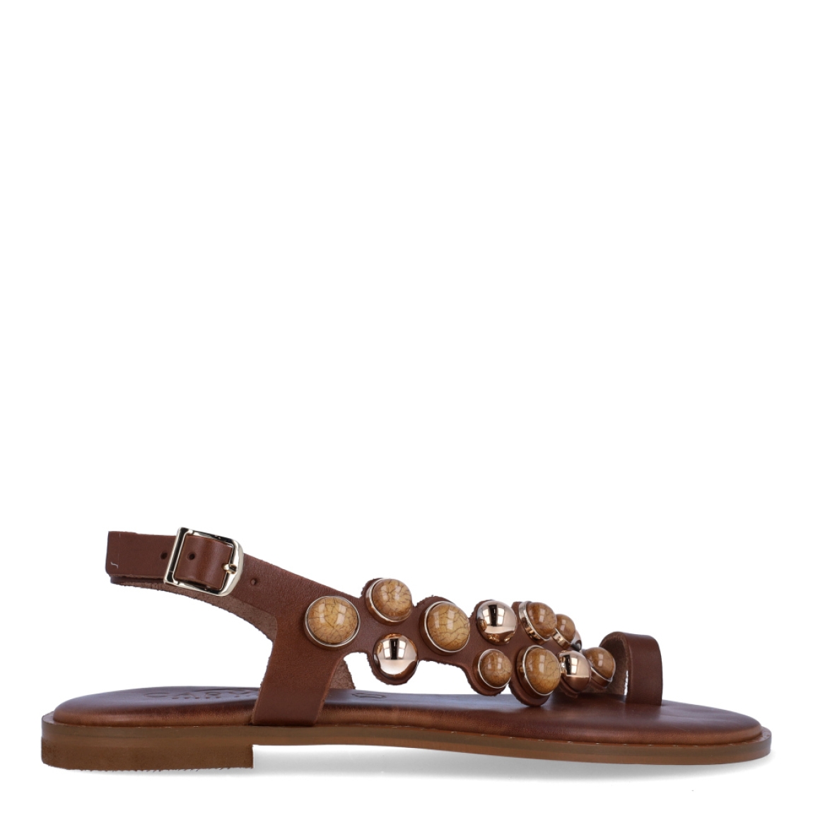 Esclavas de la marca Caryatis, modelo SENDRA. Exterior de las esclavas en piel color marrón con adornos en piedrería. Cierre de las esclavas con hebilla y suela plana. Estas esclavas Caryatis SENDRA es un producto de alta calidad, pensado en la comodidad y elegancia. No puede faltar en tu armario de temporada.
