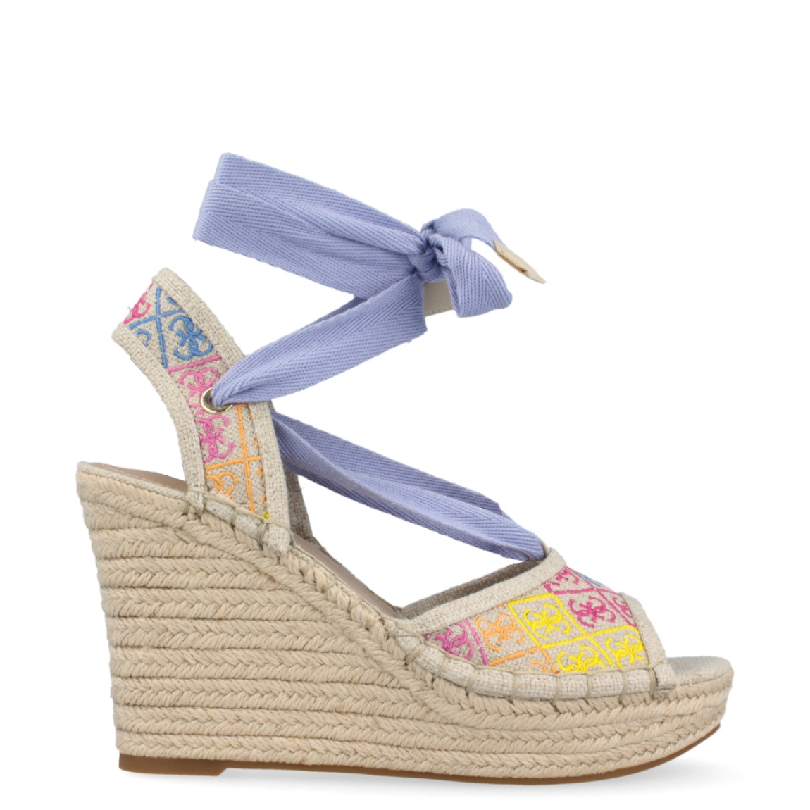Sandalia multicolor de la marca Guess, modelo Halona. Exterior de la sandalia de tela de color beig, con logo 4G bordado multicolor. Interior de la sandalia de piel de color beig. Sandalia con lazo de color lila en el tobillo. Cierre de la sandalia con velcro y correa en el tobillo. Sandalia con suela de rafia de 10 cm de cuña, con 4 cm de plataforma. La sandalia Halona de Guess es ideal para dar un toque de color a tus looks.
