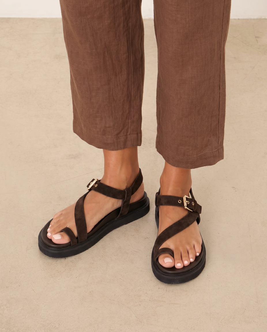 Sandalias de la marca Itse, modelo AMALIA. Elaboradas en ante color marrón oscuro con tiras en forma de S en pala. Interior en piel color marrón y cierre con hebilla en tobillo. Sandalias Itse con suela plana de goma. Estas sandalias Itse AMALIA son un complemento ideal para ti!