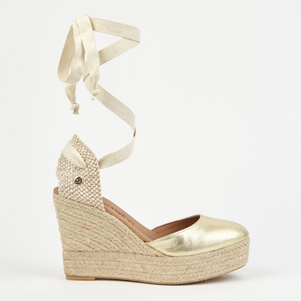 Alpargatas de la marca La Valeta, modelo CHARLENE. Exterior en piel color oro con punta redonda, forrada en microfibra transpirable. Plantilla de microfibra transpirable acolchada. Alpargatas con tiras de tela para un cierre con nudo. Plataforma en yute artesanal con cuña de 10cm de altura. Estas alpargatas La Valeta CHARLENE son ideales para esta temporada!
