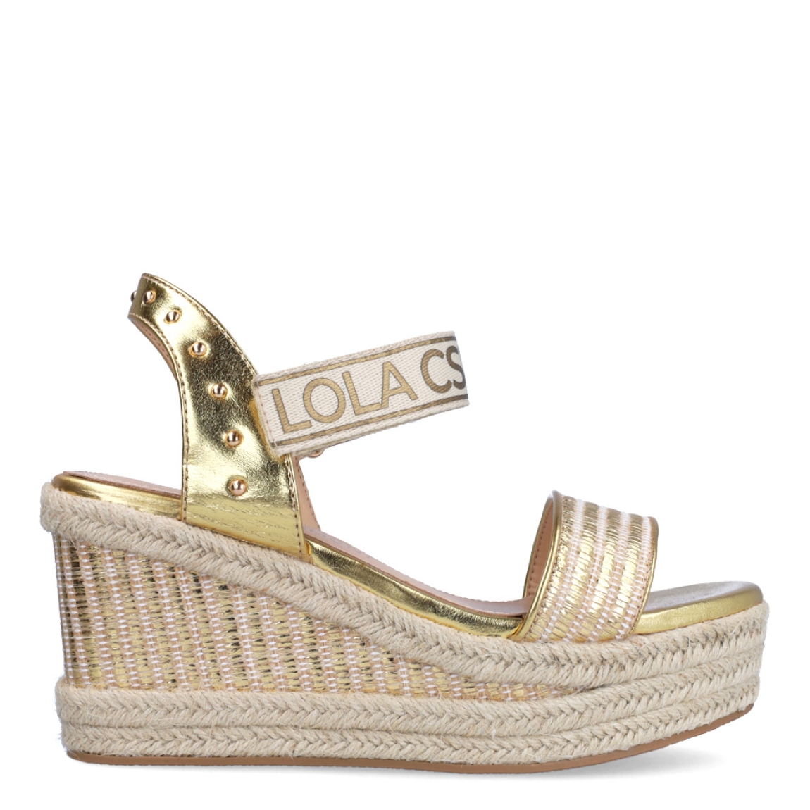 Sandalias de la marca Lola Casademunt, modelo INTI. Exterior en piel color platino con detalle de tachuelas. Interior en piel color beig. Cierre con velcro con estampado de marca. Sandalias con cuña de 9cm de altura. Estas sandalias Lola Casademunt INTI son un complemento que le dará estilo a tus looks!