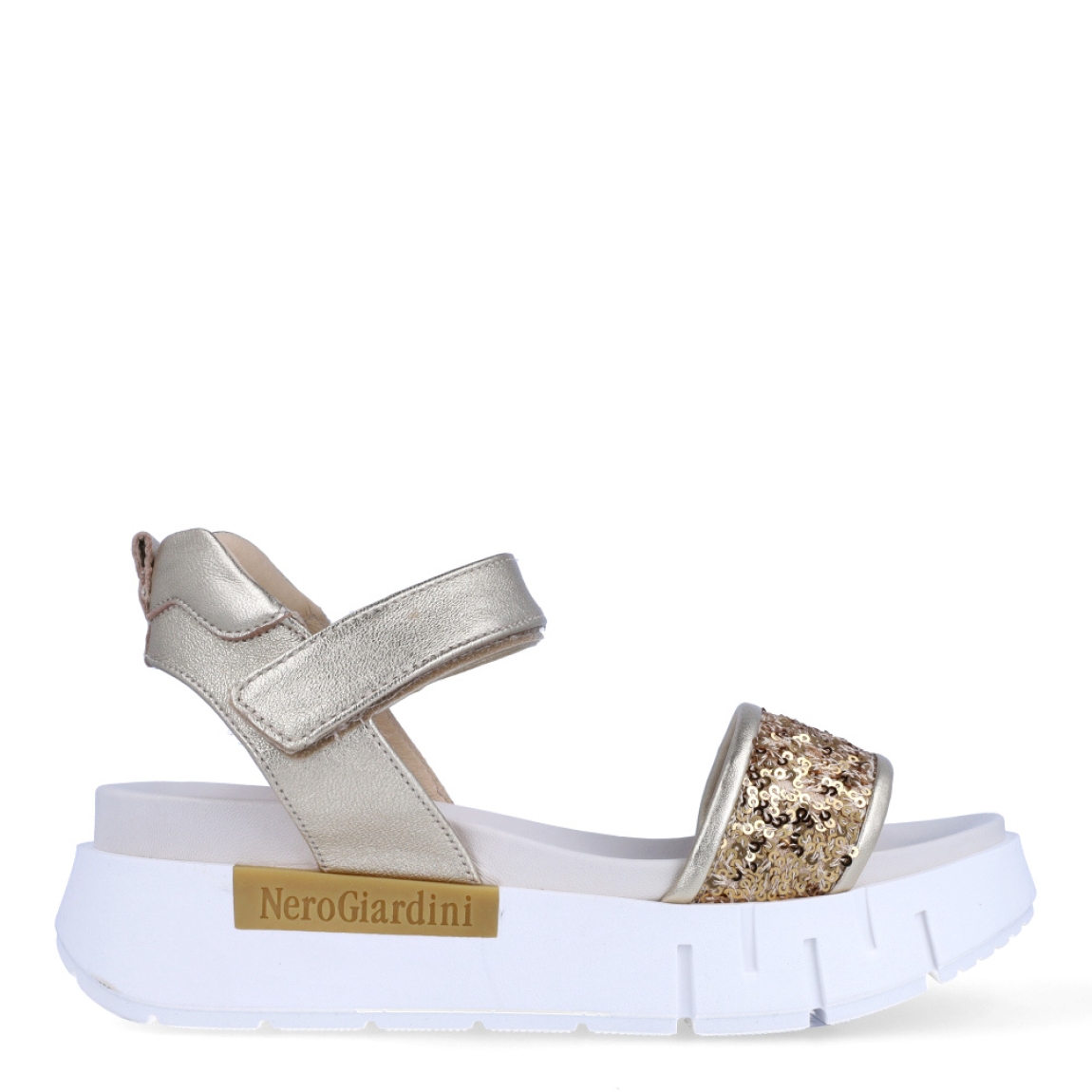Sandalias de la marca Nerogiardini, modelo JESS. Exterior de las sandalias en piel color platino con detalle de lentejuelas color dorado en la pala. Interior de las sandalias en piel color blanco. Cierre de las sandalias Nerogiardini con velcro. Sandalias con plataforma de 4cm de altura. Estas sandalias Nerogiardini JESS son un complemento clásico, inspirado en la comodidad, ligereza que necesitas en tu día a día.