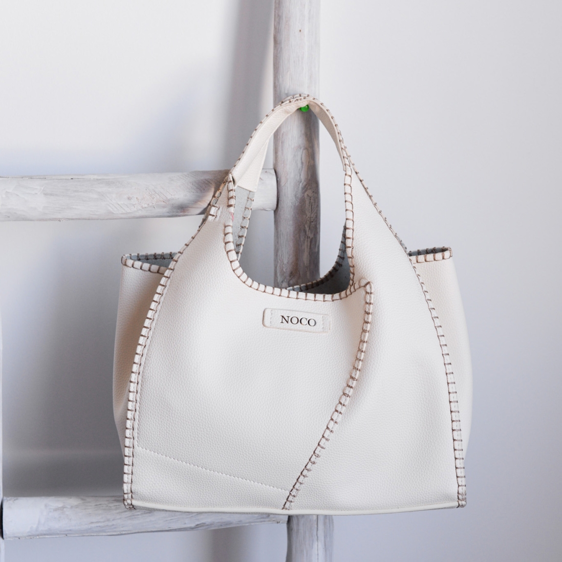 Bolso hobo Noco, modelo SHARAM. Elaborado de piel vegana color blanco. Este bolso es una pieza única que combina estilo y sostenibilidad. Su formato hobo se distingue por su trabajo de diseño original, aportando una forma sofisticada y funcional. El material de piel vegana tiene un acabado que imita a la perfección la piel real, con un suave interior similar al pelo característico de la piel auténtica, brindando una textura premium. Cierre con boton. Medidas alto 21cm y ancho 29cm.