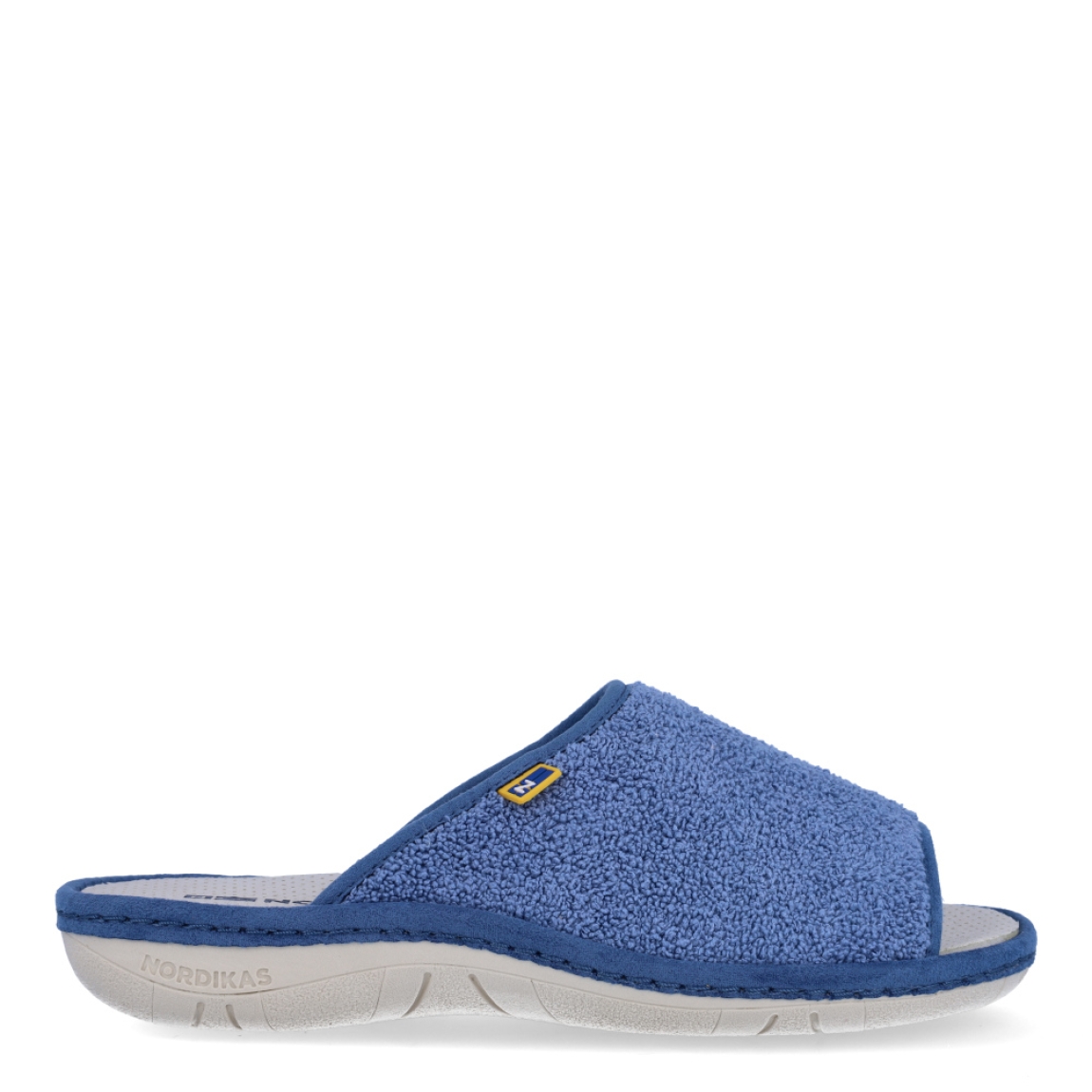 Zapatillas de casa de la marca Nordikas, modelo KAYA. Exterior de las zapatillas en toala color azul. Interior de las zapatillas en piel troquelada color blanco. Zapatilla con suela plana. Estas zapatillas Nordikas KAYA son el complemento perfecto que garantiza comodidad y ligereza al estar por casa.