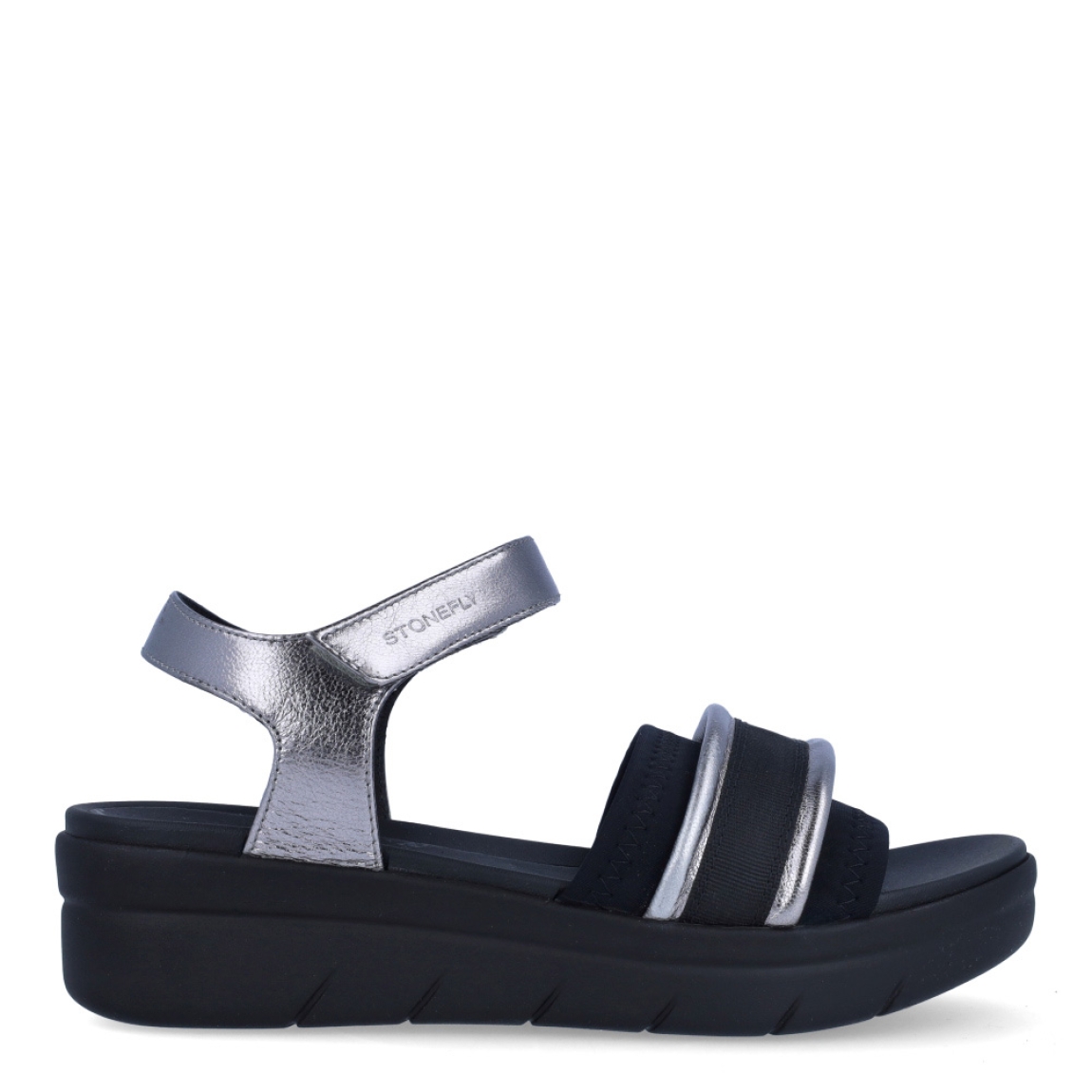 Sandalias clásicas de la marca Stonefly, modelo KIM. Exterior de las sandalias en naylon color negro con detalle en plateado. Interior de las sandalias en piel color negro. Cierre de las sandalias Stonefly con velcro y cuña de 4cm de altura. Estas sandalias Stonefly KIM son el complemento perfecto para tus looks de temporada. No te pueden faltar en el armario.