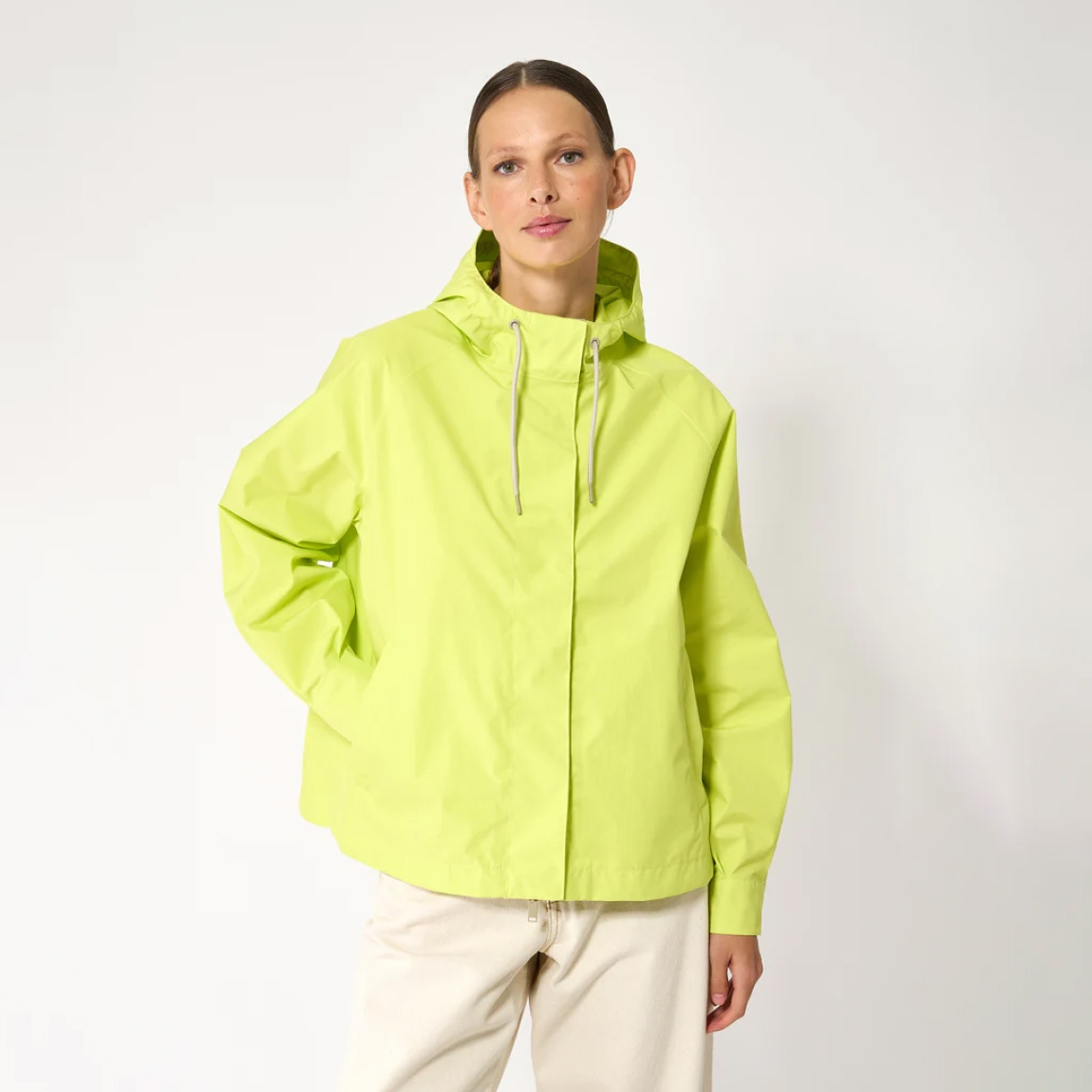 Chaqueta impermeable corta de la marca Tanta, modelo Dhuda. Tiene corte holgado y está confeccionada con un tejido de mezcla de algodón impermeable color fluor. Este material atemporal es transpirable y resistente al viento. Los detalles de la prenda incluyen costuras selladas, mangas raglán, una cremallera de doble cursor y cierres a presión ocultos. Su elegante silueta en línea A cuenta con aberturas laterales redondeadas para un look más femenino.