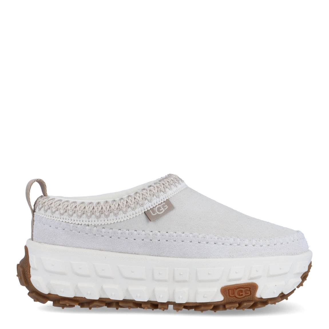 Zuecos de la marca UGG, modelo Venture Daze. Exterior en es ante color hielo. Zuecos diseñados para ofrecer un aspecto atrevido y comodidad. El Venture Daze cuenta con una suela de agarre con grandes bandas de rodadura de neumáticos para la tracción todo terreno. La parte superior de ante, el clásico UGGbraid y las emblemáticas costuras en forma de caja se asientan sobre una ligera plantilla de EVA y una entresuela de caña. Estos zuecos UGG son ideales para ir a todos lados!