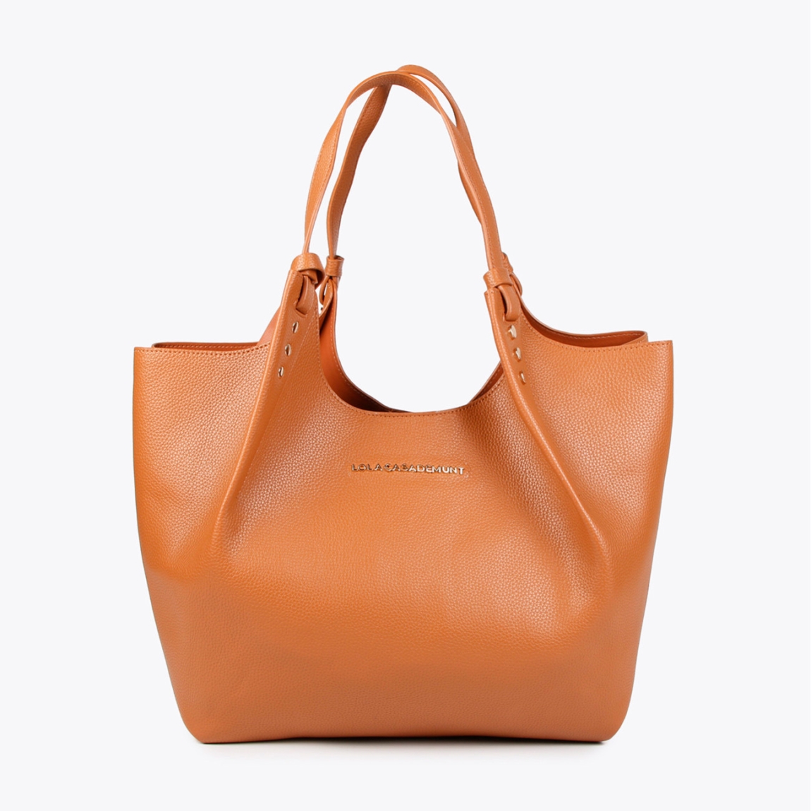 Bolso shopper de la marca Lola Casademunt, modelo ELLIE. Exterior en piel color camel y detalles de tachuelas planas. Contiene pouch interior. Cierre imantado. Asa de hombro. Las medidas son ALTO: 37 cm - LARGO: 34 cm - ANCHO: 16 cm / BANDOLERA: 87 cm. Este bolso shopper Lola Casademunt ELLIE es un complemento ideal para llevar todos tus esenciales a donde vayas!