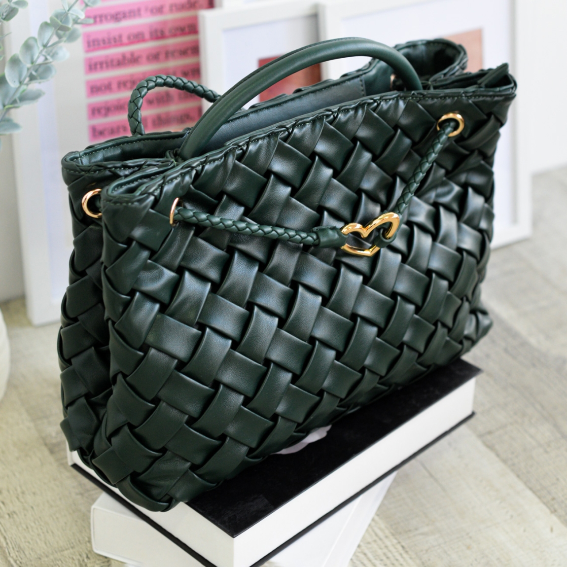 Bolso de mano de la marca Noco, modelo JULIA. Elaborado en piel sintética trenzada color verde, destaca por su textura suave y cuidada, perfecta para quienes buscan un accesorio delicado pero con personalidad. Su diseño versátil incluye un cordón decorativo trenzado que se extiende para usarlo también como bolso de hombro, adaptándose a tu estilo y necesidades en cada momento. La cremallera superior garantiza seguridad sin perder la fluidez del diseño. Como sello distintivo, lleva el ícono del corazón en oro, un detalle discreto pero lleno de significado que identifica a la perfección la esencia de Noco. Bolso Noco JULIA ideal para ti!Medidas: altura 23cm y ancho 36cm.