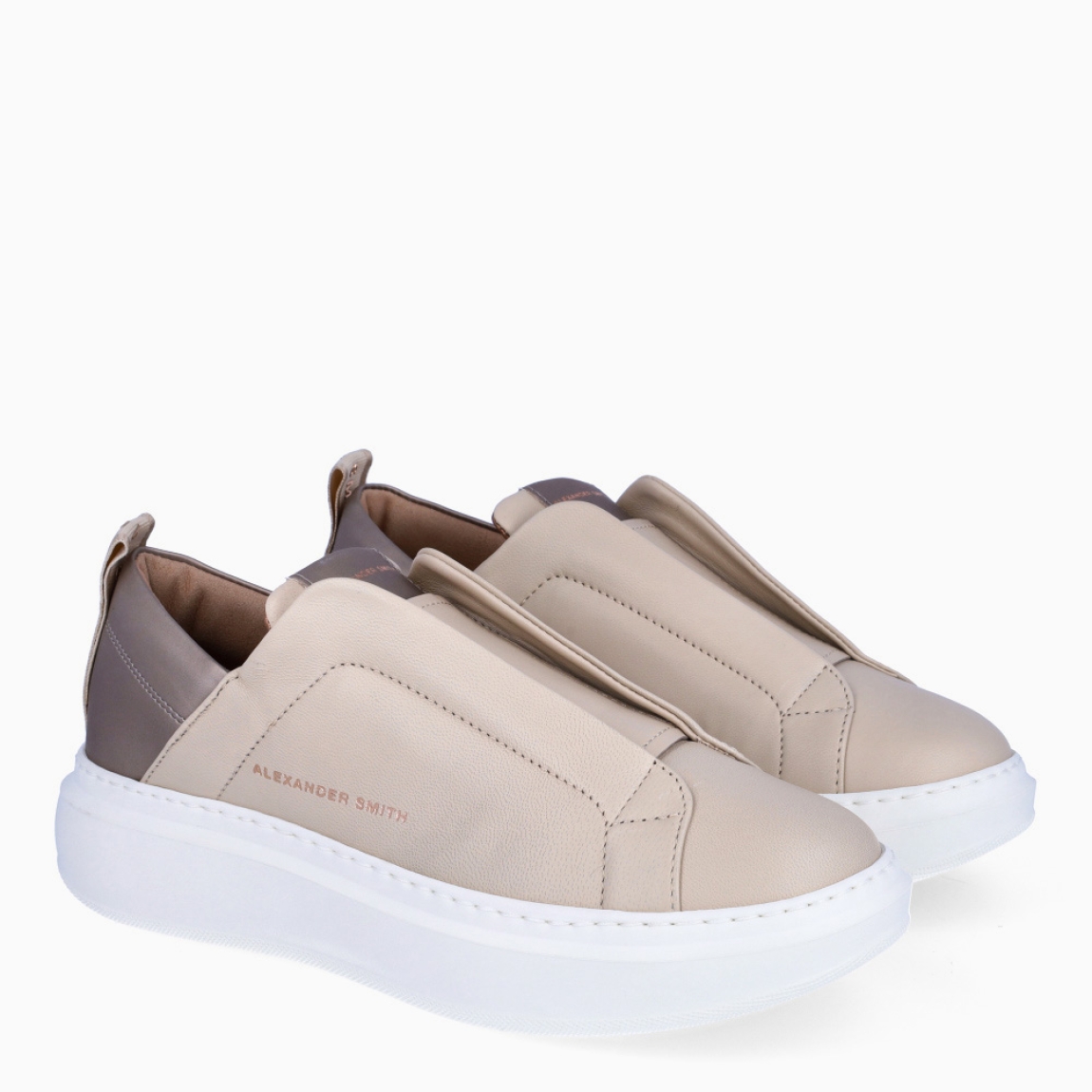 Deportivas de la marca Alexander Smith, modelo WEMBLEY SLIP-ON. Exterior de la deportiva de piel color beig. Deportiva en piel color blanco en la parte del talón. Interior de la deportiva de piel de color bronce. Cierre de la deportiva sin cordones. Deportiva con plantilla extraíble. Deportiva con logotipo en la trabilla trasera. Deportiva Alexander Smith con plataforma de 4 cm. La deportiva de Alexander Smith hace referencia al famoso estadio inglés: deportividad y elegancia se funden para dar vida a este modelo. Wembley Slip-on son las zapatillas con el equilibrio perfecto entre comodidad y estilo, elegantes y sobrias pero con un toque moderno dado por los detalles que marcan la diferencia.