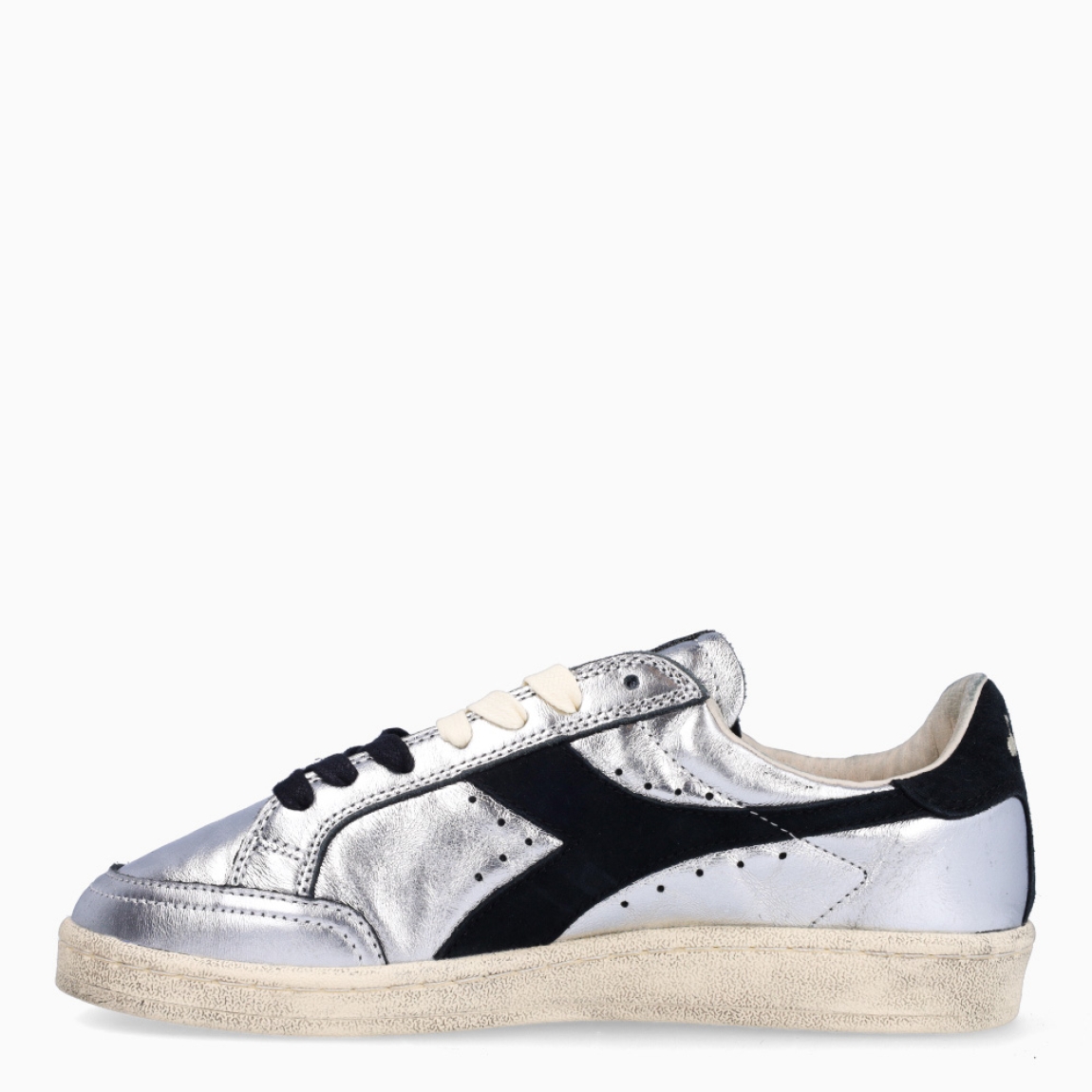 Deportivas de la marca Diadora, modelo ZULE. Exterior en piel color plata con efecto brillante y detalles en negro. Interior en textil color beig con plantilla acolchada y extraíble para máxima comodidad. Cierre con cordones de doble color: negro y beig. Suela de goma con cuña de 2cm de altura. Estas deportivas son unas clásicas ideales para llevar en tu día a día.