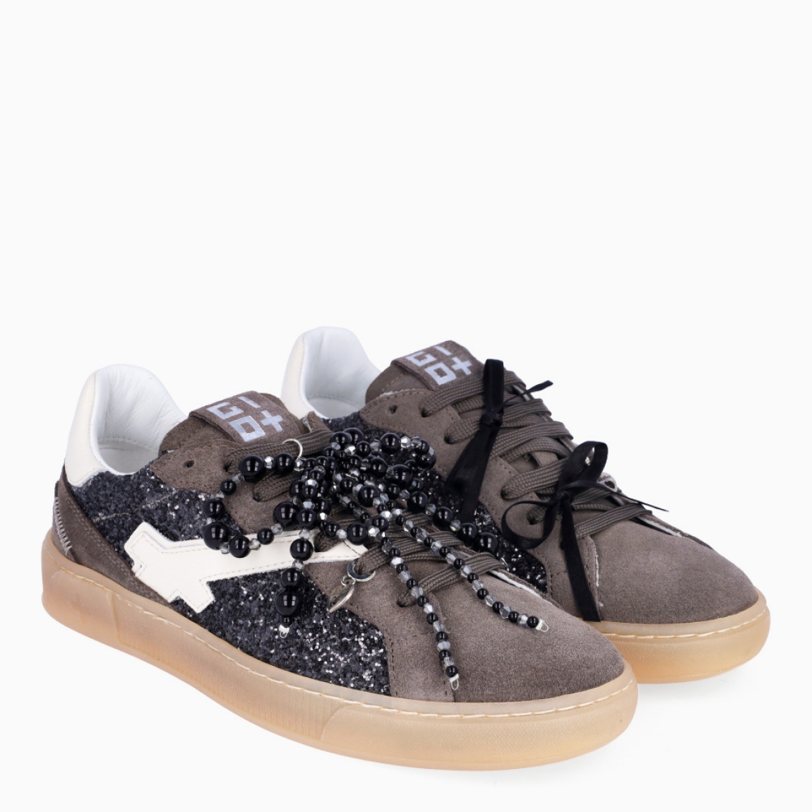 Deportivas de la marca GIO+, modelo BLUE. Exterior en ante color gris con detalle en glitter y lazo en perlas negras y dije en la pala sujetada a cordones. Interior de las deportivas en piel color blanco con plantilla acolchada y extraíble para máxima comodidad. Cierre de las deportivas con cordones gris y plataforma de 2cm de altura. Estas deportivas GIO+ BLUE tienen un estilo tendencia en esta temporada. No puede faltar en tu armario!