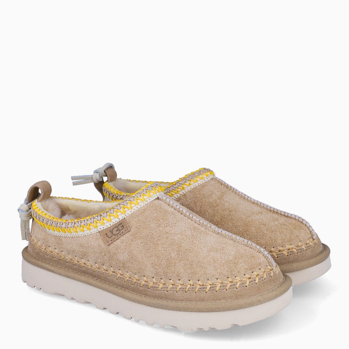 Zuecos de la marca UGG, modelo Tasman Biarritz. Exterior en piel toalla color beig con logotipo grabado y detalle de en hilo amarillo. Interior con forro y plantilla suave. Suela de los zuecos de goma con plataforma de 3cm de altura. Estos zuecos UGG Tasman Biarritz son la tendencia de temporada, combina un estilo moderno y una comodidad única que no te puede faltar!