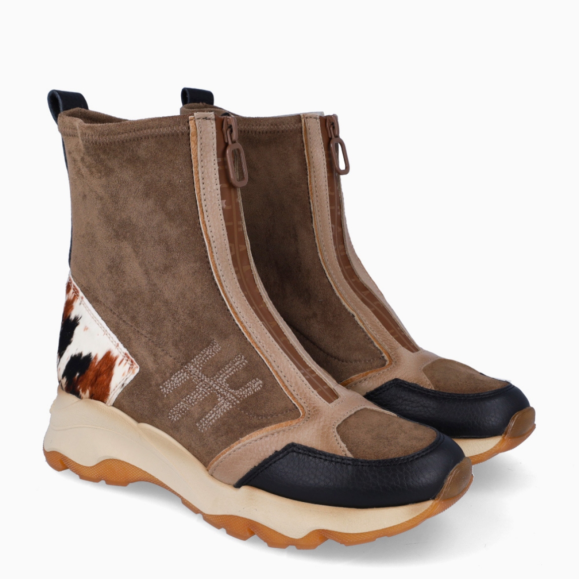 Botines de la marca Hispanitas, modelo NEPAL. Exterior ante color taupe con punta redonda y detalle de estampado animal print de vaca en talón. Interior en piel color marrón. Cierre con cremallera. Estos botines Hispanitas NEPAL son ideales para dar estilo y comodidad a tus looks de temporada!