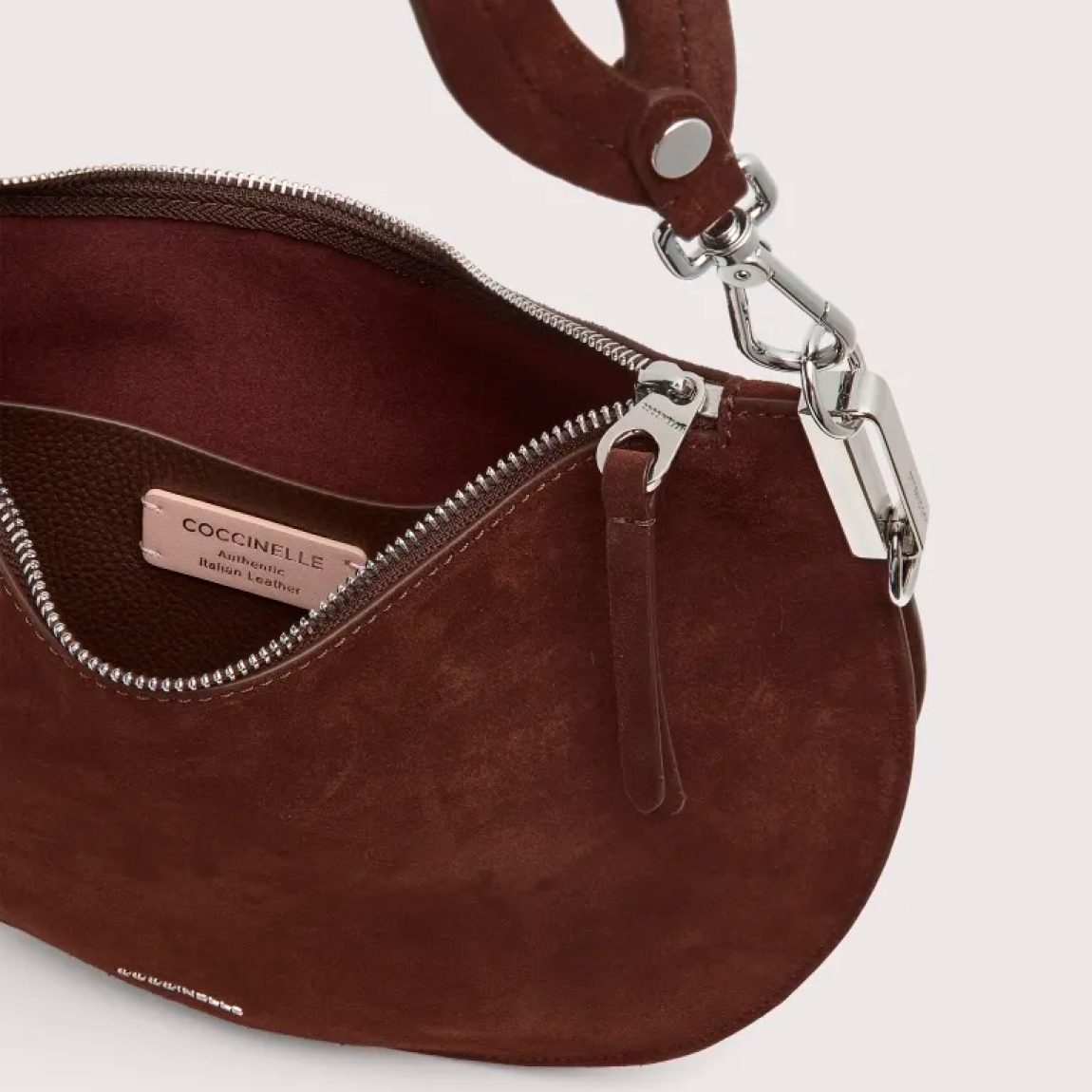 Bolso hobo de la marca Coccinelle, modelo SUNUP. Exterior en ante color marrón con detalle de logo en parte frontal. Interior amplio. Cierre con cremallera y asa de hombro. Medidas: alto 22cm y ancho 33cm. Este bolso Coccinelle SUNUP es un complemento sofisticado, ideal para combinar con tus looks de temporada!