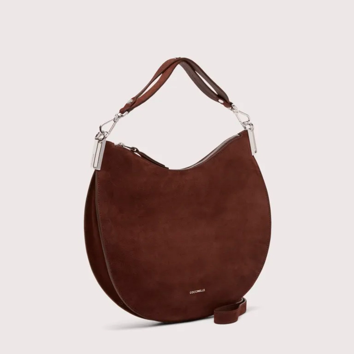 Bolso hobo de la marca Coccinelle, modelo SUNUP. Exterior en ante color marrón con detalle de logo en parte frontal. Interior amplio. Cierre con cremallera y asa de hombro. Medidas: alto 22cm y ancho 33cm. Este bolso Coccinelle SUNUP es un complemento sofisticado, ideal para combinar con tus looks de temporada!