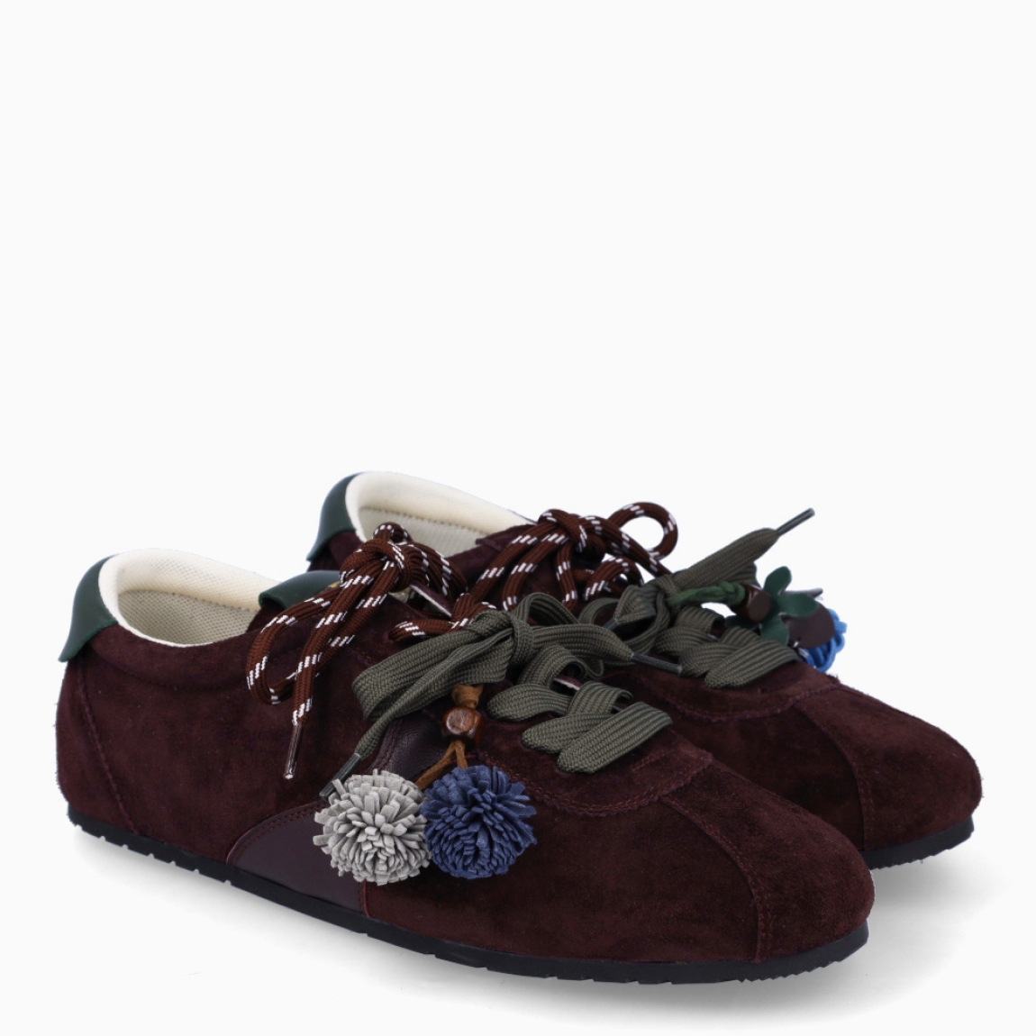 Deportivas de la marca Itse, modelo SALMA. Exterior en ante color marrón granate. Interior en textil color blanco. Cierre con cordones dobles, uno marrón y otro, verde. Deportivas Itse con tres charms sujetados a los cordones en forma de pompones y flor azul. Suela plana y de goma. Estas deportivas Itse Salma son un complemento básico y en tendencia para tus looks!