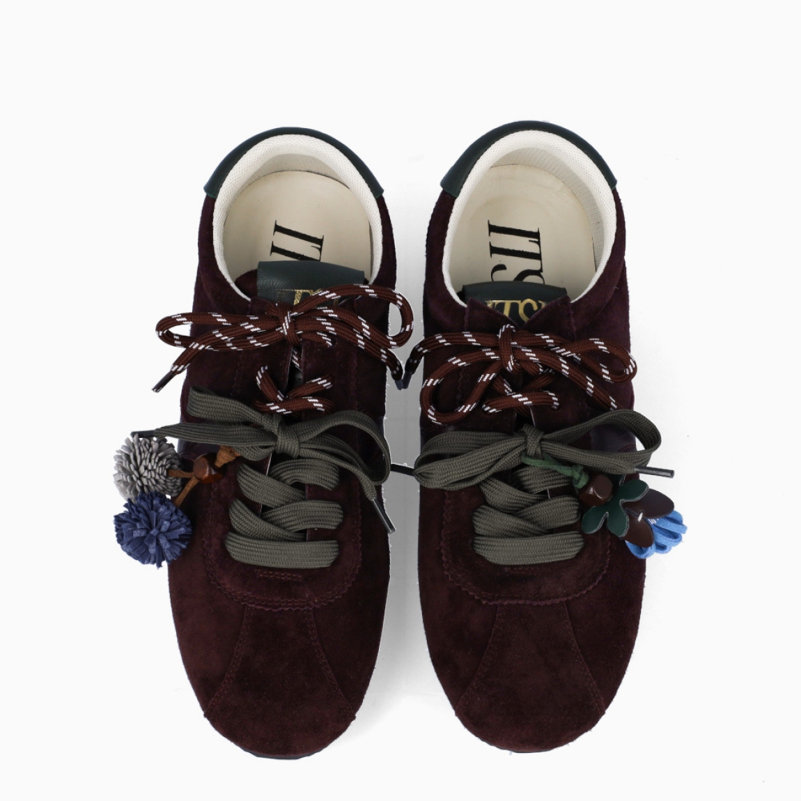 Deportivas de la marca Itse, modelo SALMA. Exterior en ante color marrón granate. Interior en textil color blanco. Cierre con cordones dobles, uno marrón y otro, verde. Deportivas Itse con tres charms sujetados a los cordones en forma de pompones y flor azul. Suela plana y de goma. Estas deportivas Itse Salma son un complemento básico y en tendencia para tus looks!