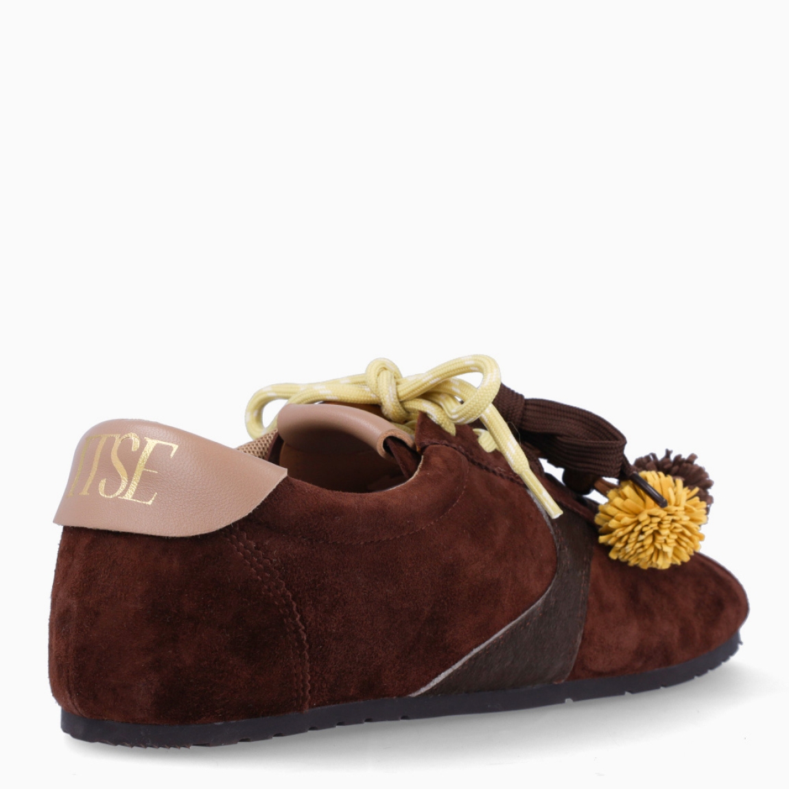 Deportivas de la marca Itse, modelo SALMA. Exterior en ante color marrón oscuro. Interior en textil color marrón. Cierre con cordones dobles, uno marrón y otro, amarillo. Deportivas Itse con tres charms sujetados a los cordones en forma de pompones y flor amarilla. Suela plana y de goma. Estas deportivas Itse Salma son un complemento básico y en tendencia para tus looks!