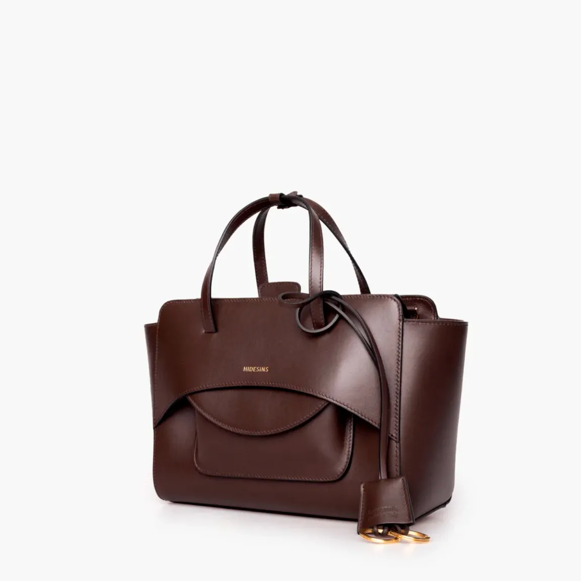 Bolso de la marca Hidesins, modelo FLAP M. Elaborado en piel de alta calidad color marrón con estampado de logotipo en frente. Bolso con botón magnético, correa bandolera ajustable y extraíble. Herrajes metálicos chapados en oro y bolsillos interiores. Medidas: alto 18cm y ancho 26cm. Este bolso Hidesins FLAP M está confeccionado con elegancia, un complemento ideal para resaltar tus looks!