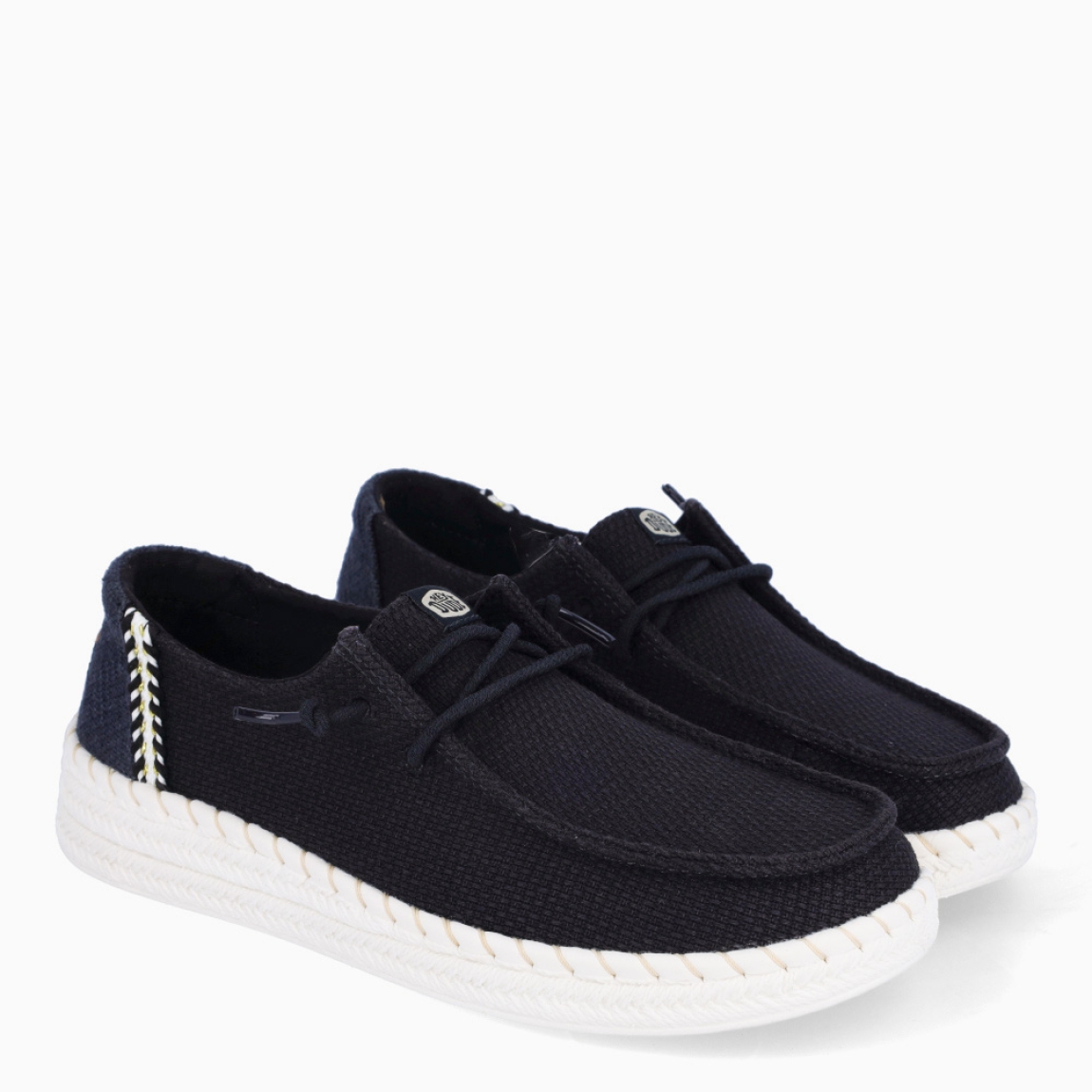 Náuticos transpirables de la marca Hey Dude, modelo WENDY. Exterior de los náuticos en textil color negro. Interior en textil color negro. Cierre de los náuticos Hey Dude con cordón elástico. Naúticos con suela de goma con 3cm de cuña. Estos náuticos Hey Dude WENDY son el complemento clásico que necesitas esta temporada. No te puede faltar en tu armario.