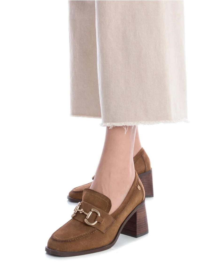 Mocasines de la marca Carmela, modelo 161138. Exterior en ante de color camel, con pieza metálica decorativa en parte frontal. Interior en piel y plantilla acolchada para máxima comodidad. Tacón de 6cm con efecto madera. Los mocasines Carmela son perfectos para tu vuelta al trabajo y los puedes combinar con todos tus outfits con su color camel. Son un MUST-HAVE este otoño-invierno.