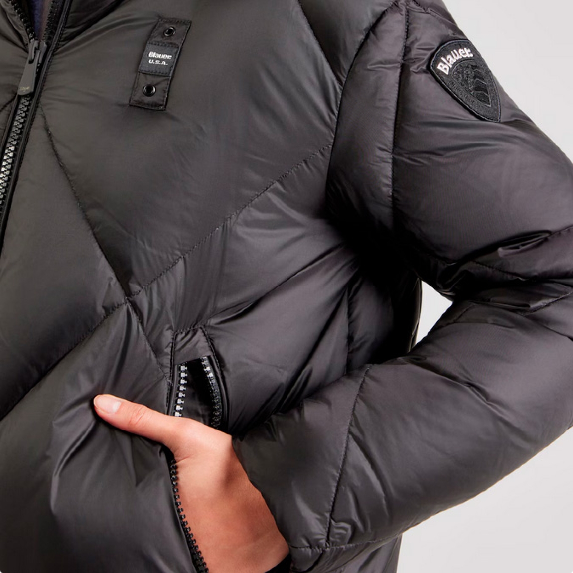 Chaqueta acolchada de la marca Blauer, modelo LAMARTINE. Chaqueta elaborada en naylon de color negro. Prenda icónica Blauer con relleno natural, cálido y poco voluminoso. Capucha fija con elástico rayado. Cierre con cremallera. Chaqueta Blauer LAMARTINE, complemento ideal para esta temporada!