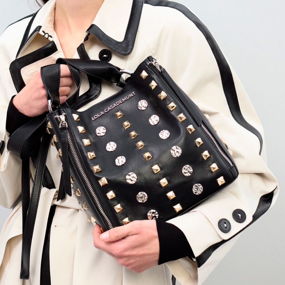 Bolso de hombro de la marca Lola Casademunt, modelo GIGI. Bolso elaborado en polipiel color negro con diseño atrevido con tachas doradas y brillantes. Confeccionado en cuero sintético de alta calidad, es perfecto para añadir un toque de glamour rockero a tu look urbano. Incluye cierre de cremallera y correa ajustable para mayor comodidad.ALTO 24cm ANCHO 22.5cm PROFUNDIDAD 14cm