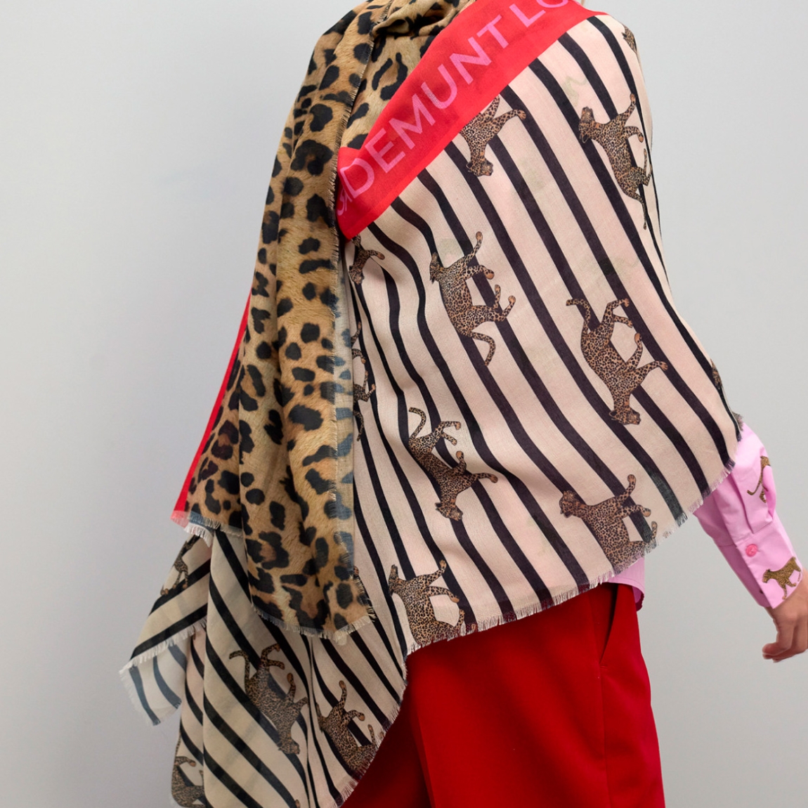 Fular de la marca Lola Casademunt, modelo L070. Fular con diseño único que combina rayas clásicas con estampado de leopardos. Confeccionado en tejido suave y ligero, ideal para todo el año. Detalle de borde contrastado en rojo con logo de la marca.