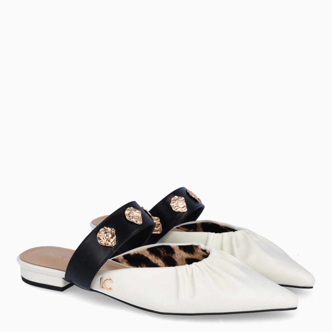 Salones destalonados de la marca Lola Casademunt, modelo ELOISE. Elaborado en piel color blanco con efecto corrugado, punta de lápiz y detalle de tira negra con adornos dorados en pala. Salones planos para máxima comodidad. Salones Lola Casademunt ELOISE, ideal para combinar con atuendos casuales o de oficina.