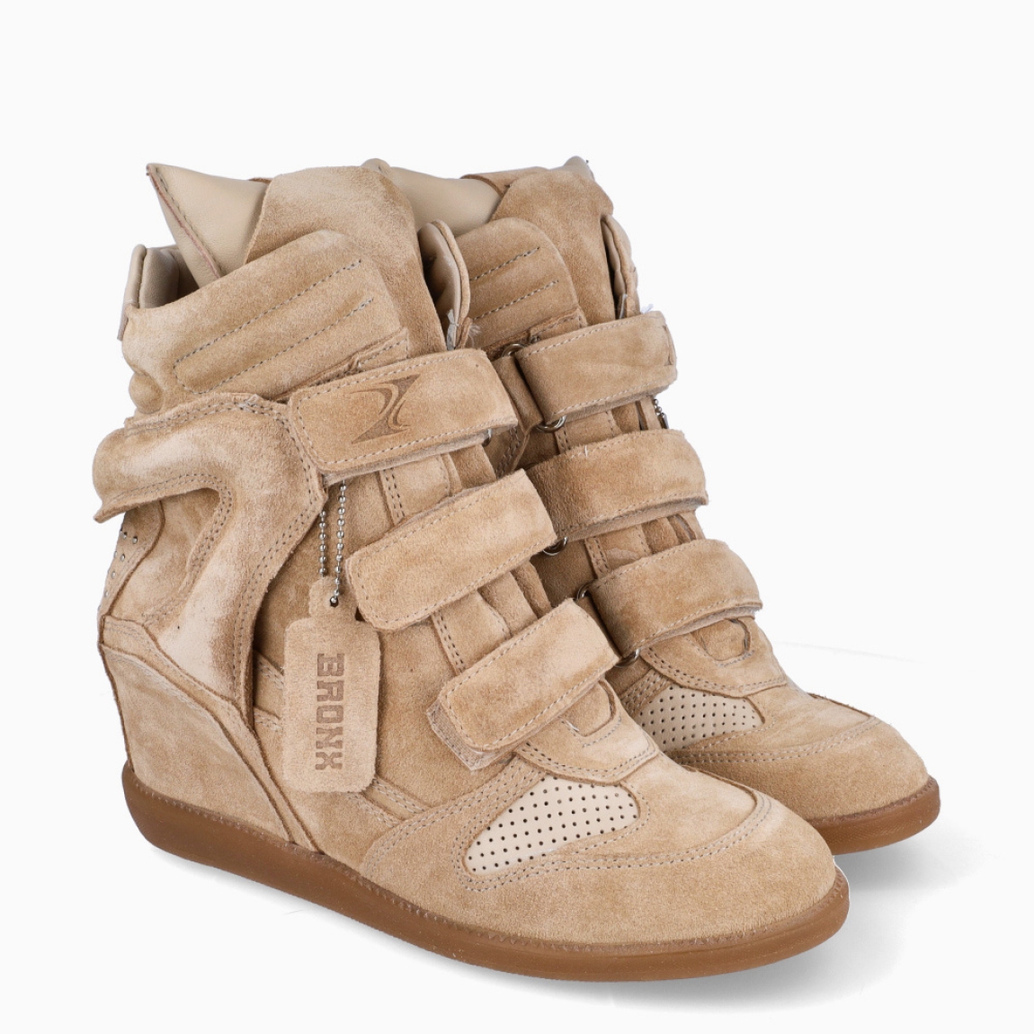 Botines de la marca Bronx, modelo JAE-YY. Elaborados en ante color beig con detalle en rejillas y efecto acolchado. Cierre de los botines con tres velcros en toda la pala. Interior con plantilla acolchada extraíble para máxima comodidad. Suela con cuña interior de 5cm de altura. Estos botines Bronx JAE-YY son un complemento que combina comodidad deportivas con toque femenino. Ideal en ofrecer un look moderno y divertido, además de una comodidad inigualable!