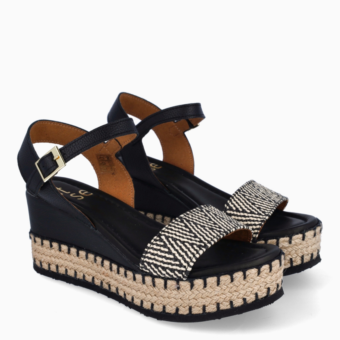 Sandalias de la marca Itse, modelo JUANA. Exterior de las sandalias en rafia color negro y blanco. Interior de las sandalias en piel color negro. Cierre de las sandalias Itse con hebilla en tobillo y cuña de 8cm de altura. Estas sandalias Itse JUANA son el complemento ideal para crear diferentes looks esta temporada, y sobre todo, gozar de una comodidad espectacular en tu día a día.