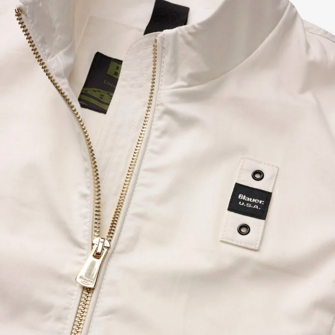 Chaqueta de la marca Blauer, modelo BLAKE. Chaqueta elaborada en algodón con cuello coreano color blanco. Las líneas son fluidas y esenciales con detalles modernos y refinados para un estilo casual pero elegante. Cierre de chaqueta Blauer con cremallera. Bolsillos dobles abiertos y con automático. Puño cerrado con cremallera profunda. Bolsillo interno con Velcro. Parche y presilla con logo. Chaqueta Blauer BLAKE ideal para ti!