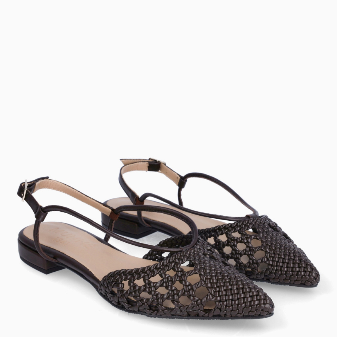 Salones destalonados de la marca Munné, modelo BURGA. Salones elaborados en piel trenzada color marrón. Salones en punta de lápiz con dos tiras en pala que llevan hasta el cierre con hebilla en talón. Suela de goma plana. Estos salones Munné BURGA son un complemento con estilo, elegancia y comodidad, perfectos para la temporada!