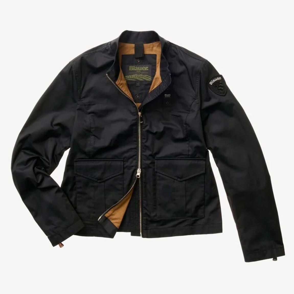 Chaqueta de la marca Blauer, modelo BLAKE. Chaqueta de algodón en color negro con cuello coreano. Las líneas son fluidas y esenciales con detalles modernos y refinados para un estilo casual pero elegante. Cierre de chaqueta Blauer con cremallera, bolsillos dobles abiertos y con automático, puño cerrado con cremallera profunda, bolsillo interno con Velcro. Parche y presilla con logo. Chaqueta Blauer BLAKE, complemento ideal para temporada!