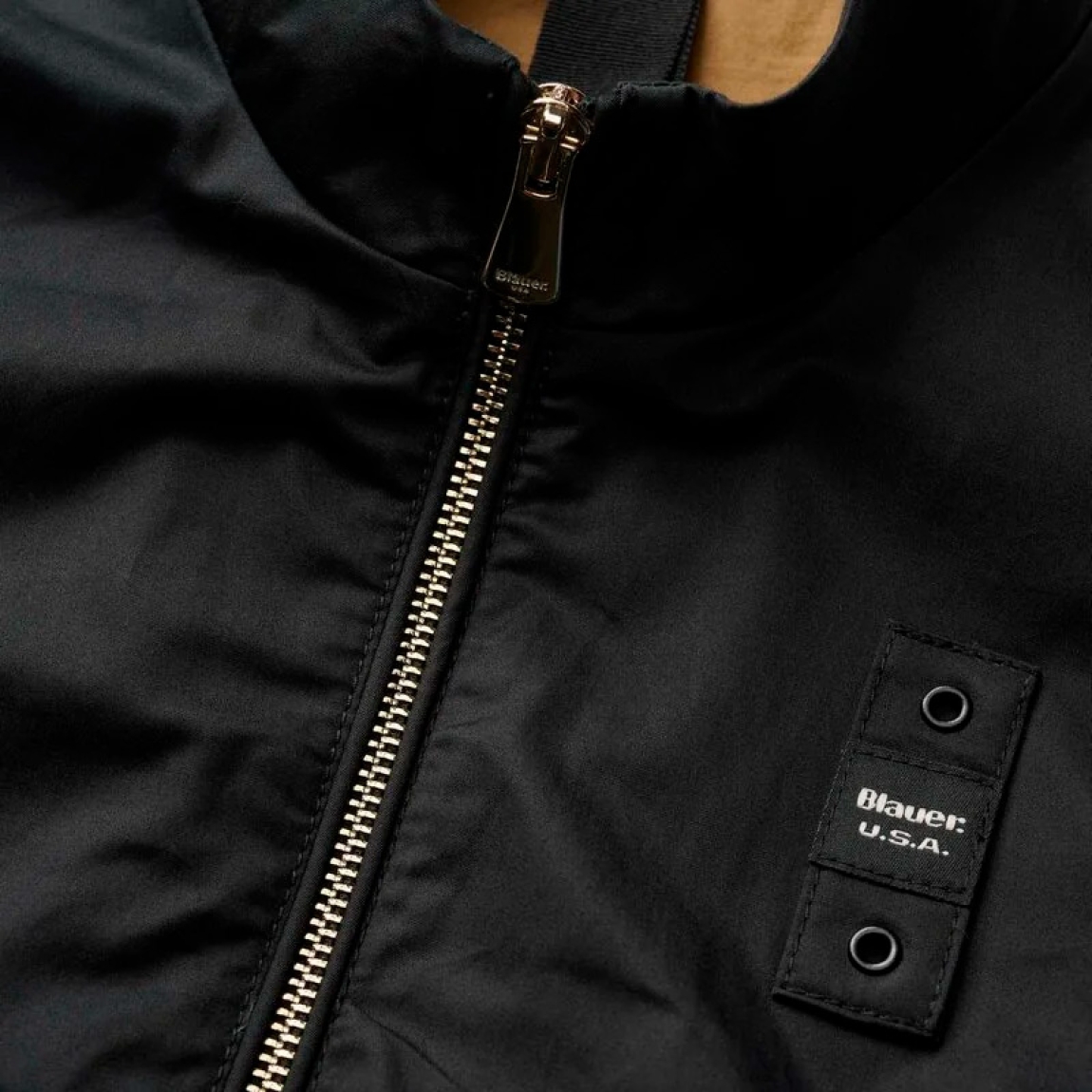 Chaqueta de la marca Blauer, modelo BLAKE. Chaqueta de algodón en color negro con cuello coreano. Las líneas son fluidas y esenciales con detalles modernos y refinados para un estilo casual pero elegante. Cierre de chaqueta Blauer con cremallera, bolsillos dobles abiertos y con automático, puño cerrado con cremallera profunda, bolsillo interno con Velcro. Parche y presilla con logo. Chaqueta Blauer BLAKE, complemento ideal para temporada!