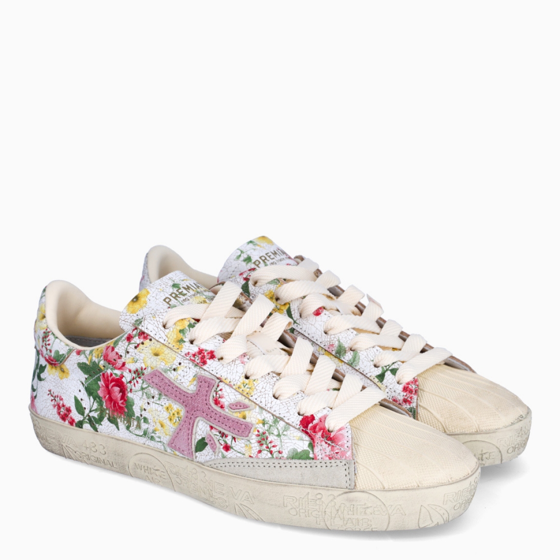 Deportivas de la marca Premiata, modelo STEVEND. Exterior de las deportivas en piel color blanco con estampado de flores y logo de color rosa. Interior de las deportivas en piel color blanco. Cierre de las deportivas con cordones blancos. Deportivas Premiata Stevend tienen el diseño perfecto para temporada, no puede faltar este modelo clásico en tu armario!